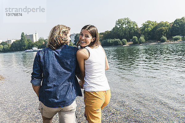 Glückliches verliebtes junges Paar beim Spaziergang am Flussufer