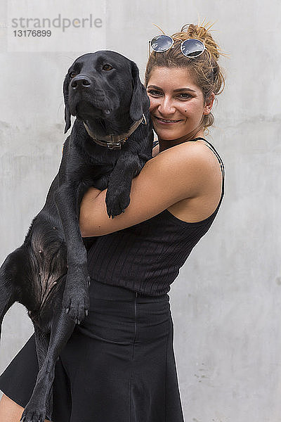 Porträt einer glücklichen jungen Frau mit ihrem schwarzen Hund