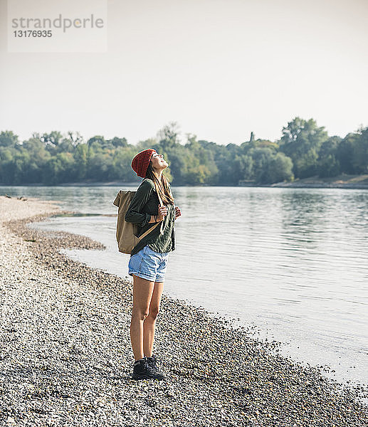 Glückliche junge Frau steht am Flussufer