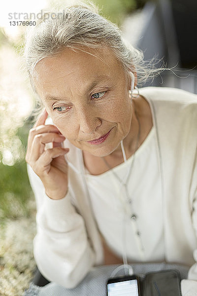 Porträt einer älteren Frau mit Mobiltelefon und Kopfhörern