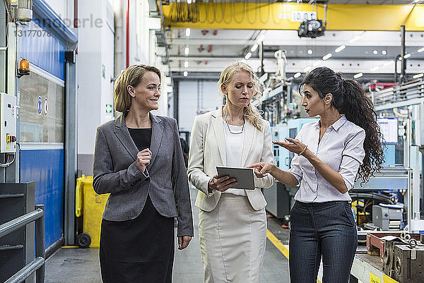 Drei Frauen mit Tabletten im Gespräch in der Fabrikhalle