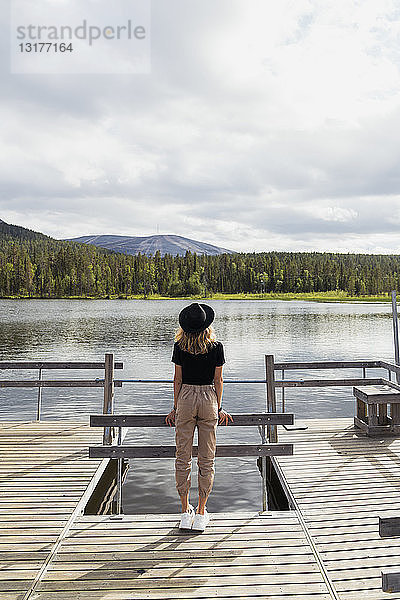 Finnland  Lappland  Frau mit Hut auf einem Steg an einem See stehend