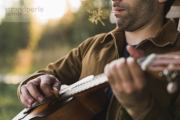 Nahaufnahme eines jungen Mannes  der die Ukulele spielt