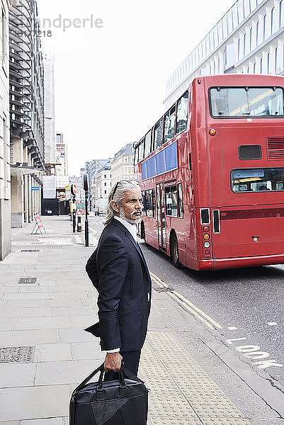 UK  London  leitender Geschäftsmann mit Gepäck wartet am Zebrastreifen