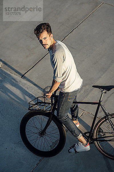 Junger Mann mit Pendler-Fixie-Fahrrad auf Betonplatten