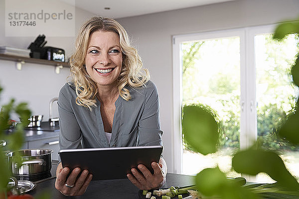 Lächelnde Frau benutzt Tablette in der Küche