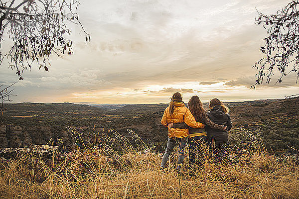 Spanien  Alquezar  drei Freunde umarmen sich auf einem Hügel mit Blick auf die Landschaft