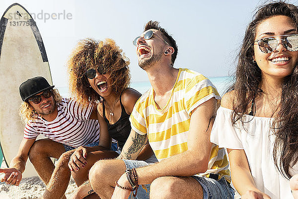 Freunde sitzen am Strand und haben Spaß