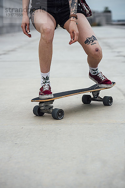 Beine einer jungen Frau  die auf einer Promenade Carver-Skateboard fährt