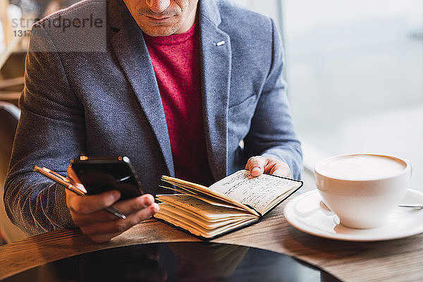 Geschäftsmann sitzt im Restaurant  trinkt Kaffee und schaut in sein Notizbuch