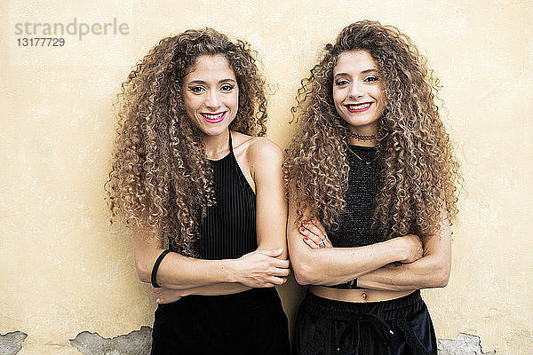 Porträt nebeneinander stehender lachender Zwillingsschwestern