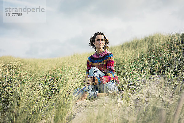 Reife Frau entspannt sich am Strand  sitzt in den Dünen