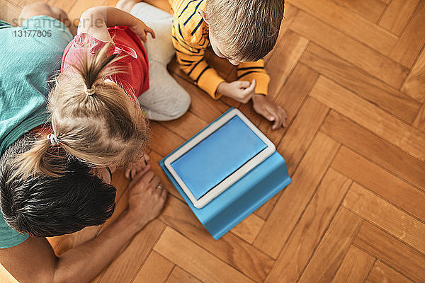 Vater und seine Kinder verwenden zu Hause ein digitales Tablet  Draufsicht