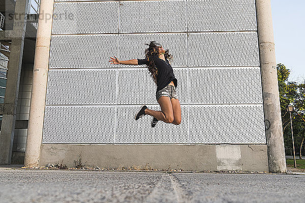 Überschwängliche junge Frau springt im Freien