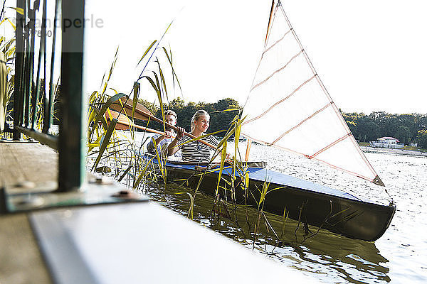 Junges Paar geniesst eine Kanufahrt mit Segeln auf einem See