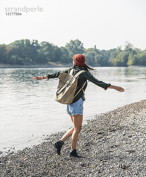 Unbeschwerte junge Frau beim Spaziergang am Flussufer