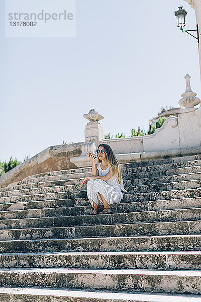 Spanien  Valencia  Frau sitzt auf einer Treppe und benutzt ein Smartphone
