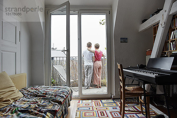 Rückansicht eines Paares  das zu Hause auf dem Balkon steht