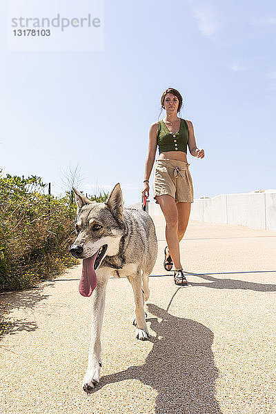 Junge Frau geht mit ihrem Hund auf der Promenade spazieren