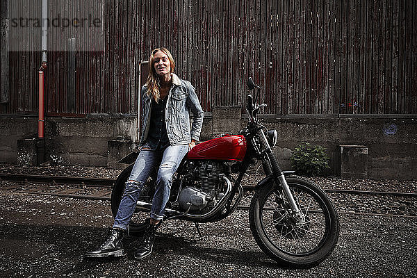 Porträt einer selbstbewussten jungen Frau mit Motorrad