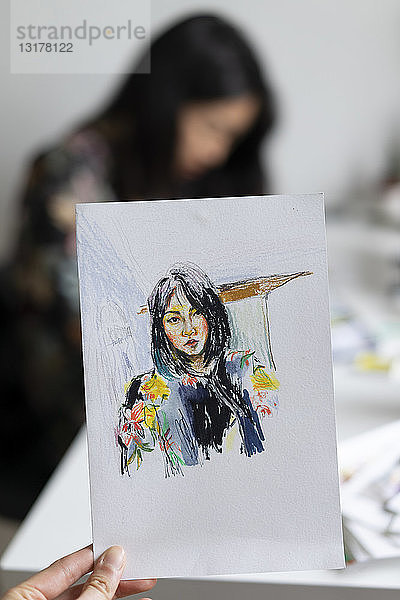 Frauenhand haltende Zeichnung eines Frauenporträts