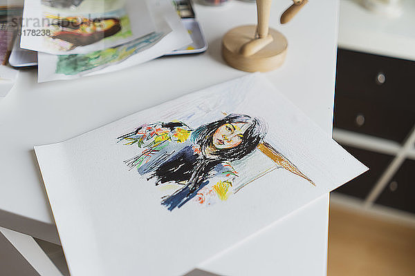Zeichnung eines Frauenporträts  das auf einem Arbeitstisch in einem Atelier liegt