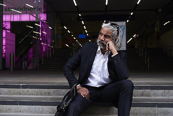 Stilvoller Senior-Geschäftsmann sitzt auf einer Treppe im Freien