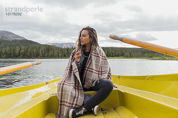 Finnland  Lappland  Frau mit einer Decke auf einem Boot auf einem See
