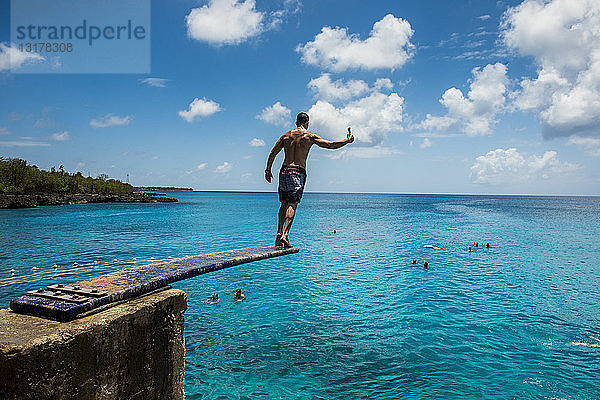 Karibik  Kolumbien  San Andres  Mann auf Sprungbrett über türkisfarbenem Wasser