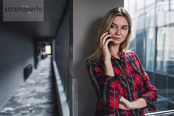 Porträt einer jungen Frau am Telefon in einem modernen Bürogebäude