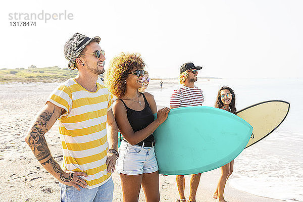 Gruppe von Freunden  die mit Surfbrettern am Strand spazieren gehen