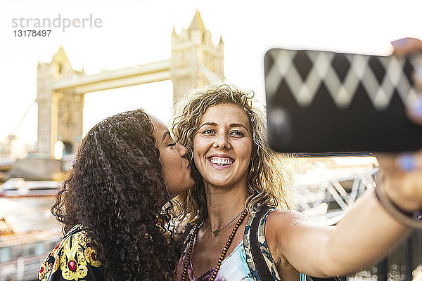 Großbritannien  London  zwei Freunde bei einem Selfie mit der Tower Bridge im Hintergrund