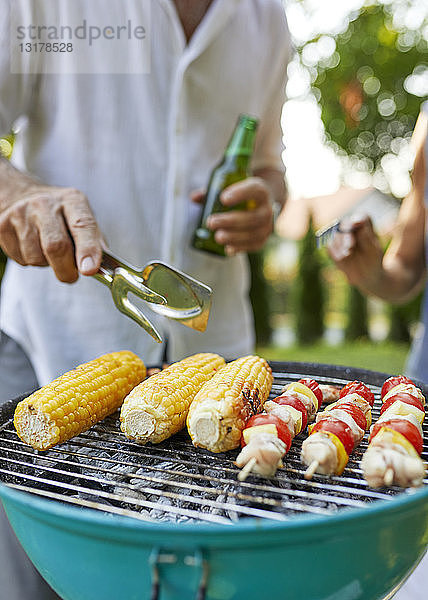 Maiskolben und Fleischspieß auf dem Grill beim Barbecue im Garten