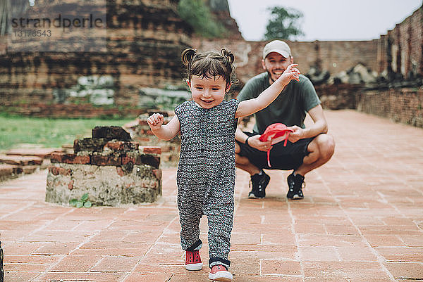 Thailand  Ayutthaya  Vater beobachtet sein kleines Mädchen beim Spaziergang in den alten Ruinen eines Tempels im Wat Mahathat