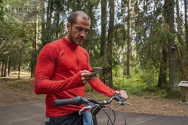 Mountainbiker mit Smartphone in einem Wald