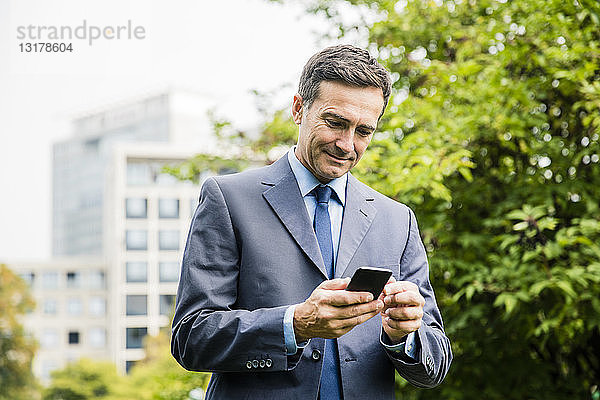 Geschäftsmann benutzt Mobiltelefon im Stadtpark