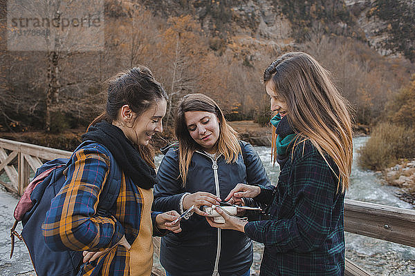 Spanien  drei junge Frauen betrachten Sofortbilder auf einer Brücke im Ordesa-Nationalpark