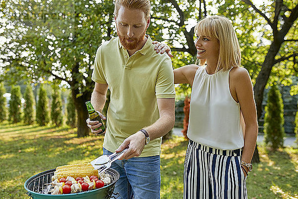 Junges Paar beim Grillen im Garten