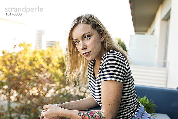 Porträt einer blonden jungen Frau auf dem Balkon