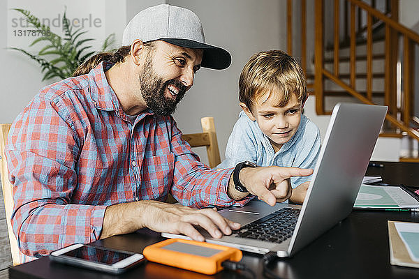 Vater und Sohn benutzen gemeinsam einen Laptop