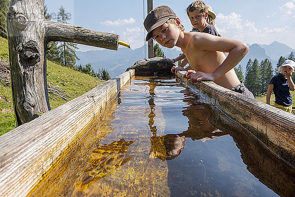 Jungen an einem Brunnen in einer Berglandschaft