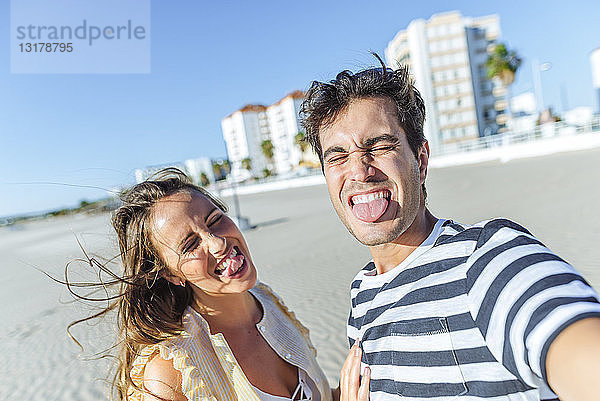Lustige Selbstgefälligkeit eines glücklichen jungen Paares am Strand