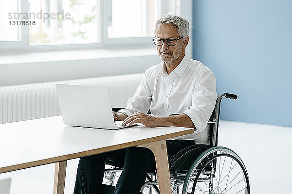 Behinderter Manager im Rollstuhl  der im Büro arbeitet