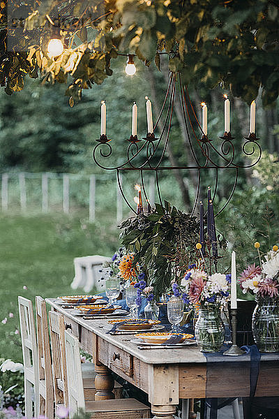 Festlich gedeckter Tisch mit Kerzen unter einem Baum