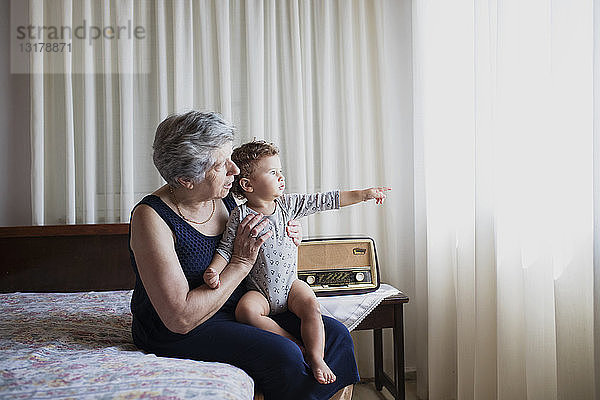 Großmutter sitzt mit ihrem Enkel im Bett