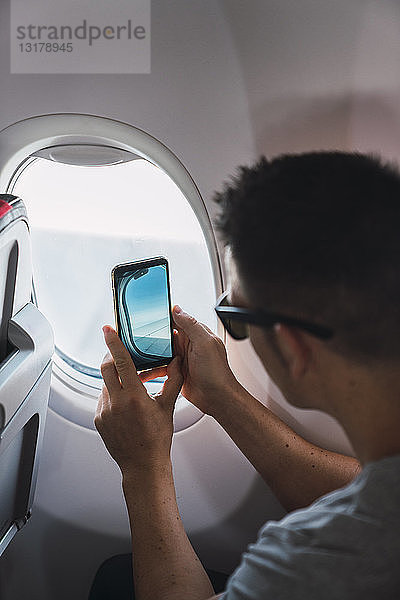 Mann im Flugzeug  Smartphone benutzen  fotografieren  Flugzeugfenster