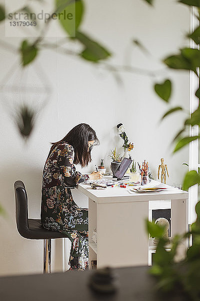 Illustratorin malt am Arbeitstisch in einem Atelier