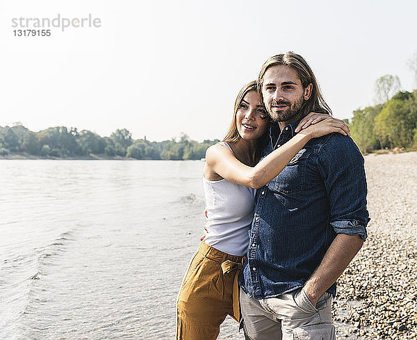 Glückliches junges verliebtes Paar umarmt sich am Flussufer