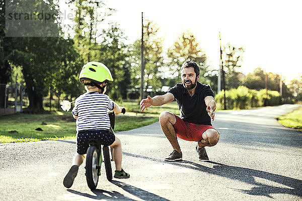 Vater unterstützt kleinen Sohn auf dem Fahrrad