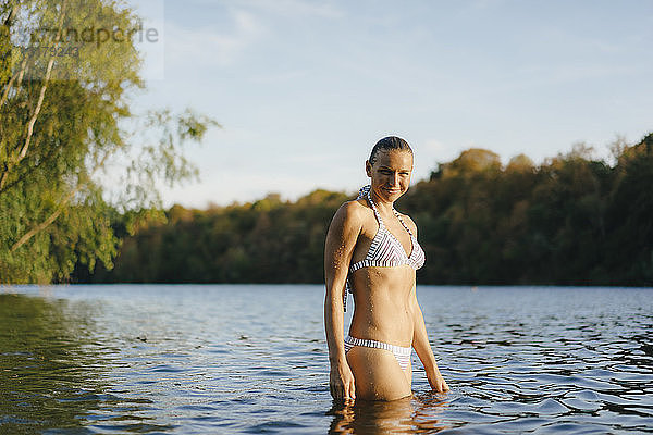 Porträt einer lächelnden Frau im Bikini in einem See
